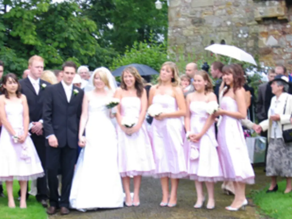 Bride, groom, and five bridesmaids in pink dresses standing outside church