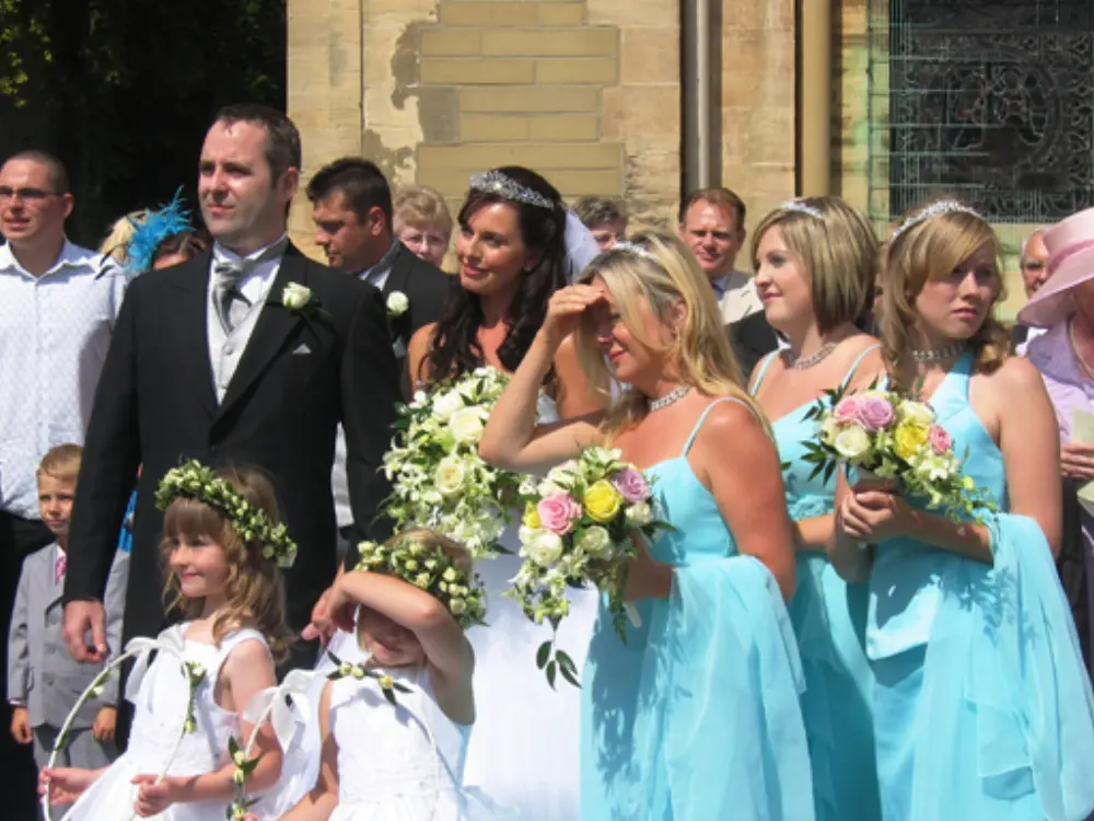 Bride, groom, flower girls and bridesmaids in turquoise blue gowns outside church