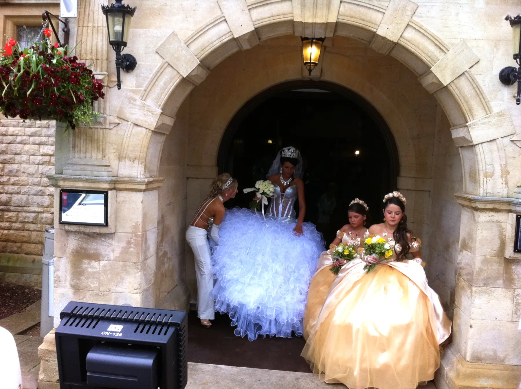 Gypsy wedding bride in dramatic ruffled ballgown and crystal tiara emerging from church archway
