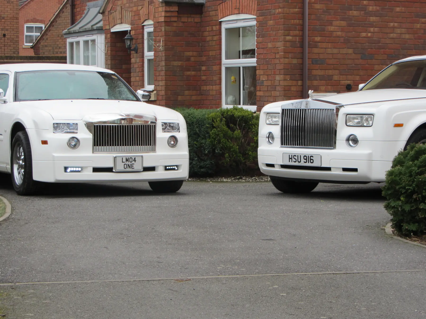 Front grilles of white Rolls-Royce Phantom and Rolls-Royce style limousine parked side by side