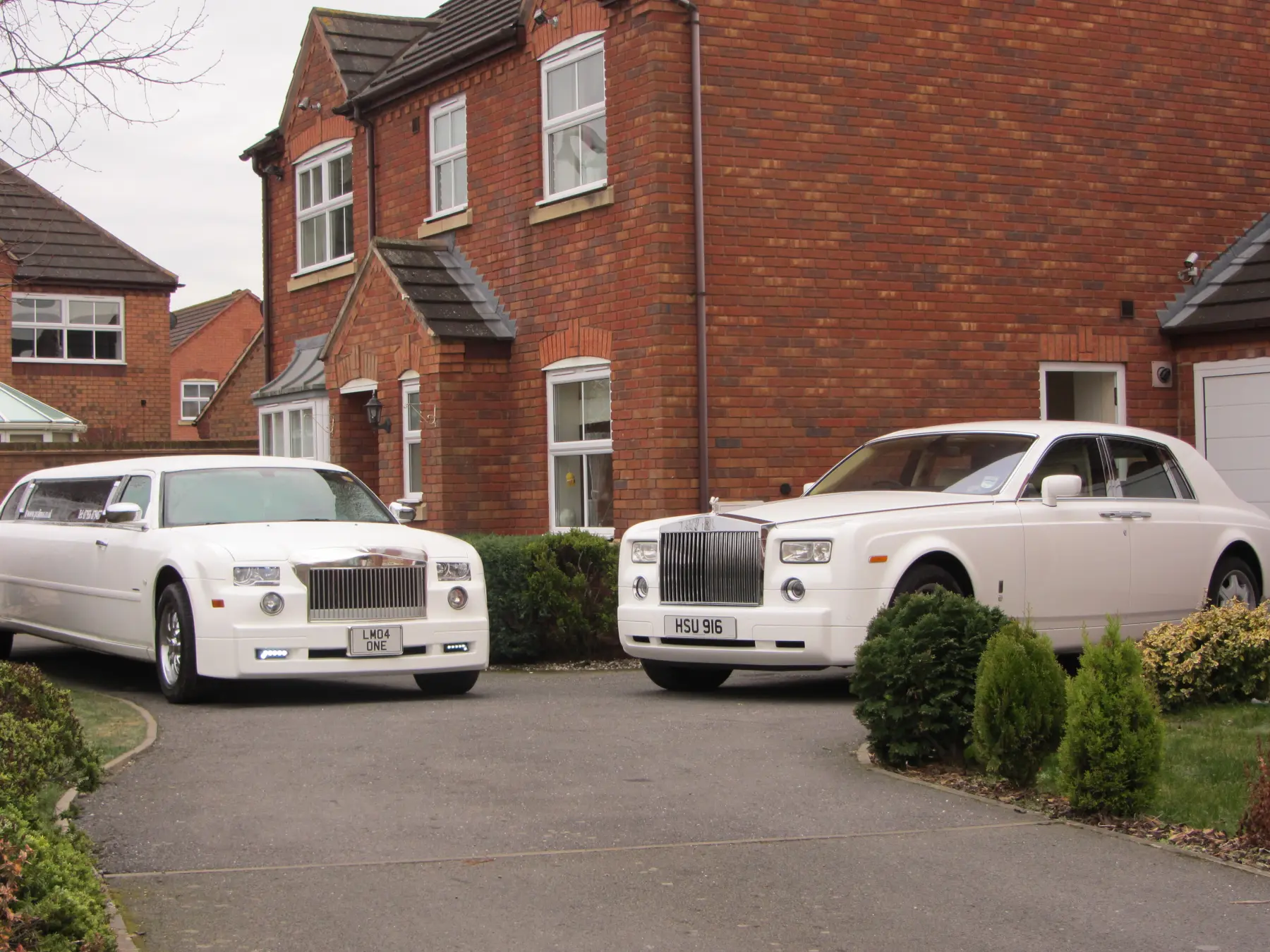 White Rolls-Royce Phantom and matching white Rolls-Royce style stretch limousine parked on driveway