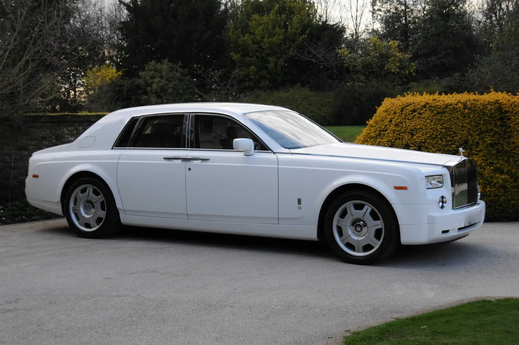 Side profile view of white Rolls-Royce Phantom luxury wedding car on driveway